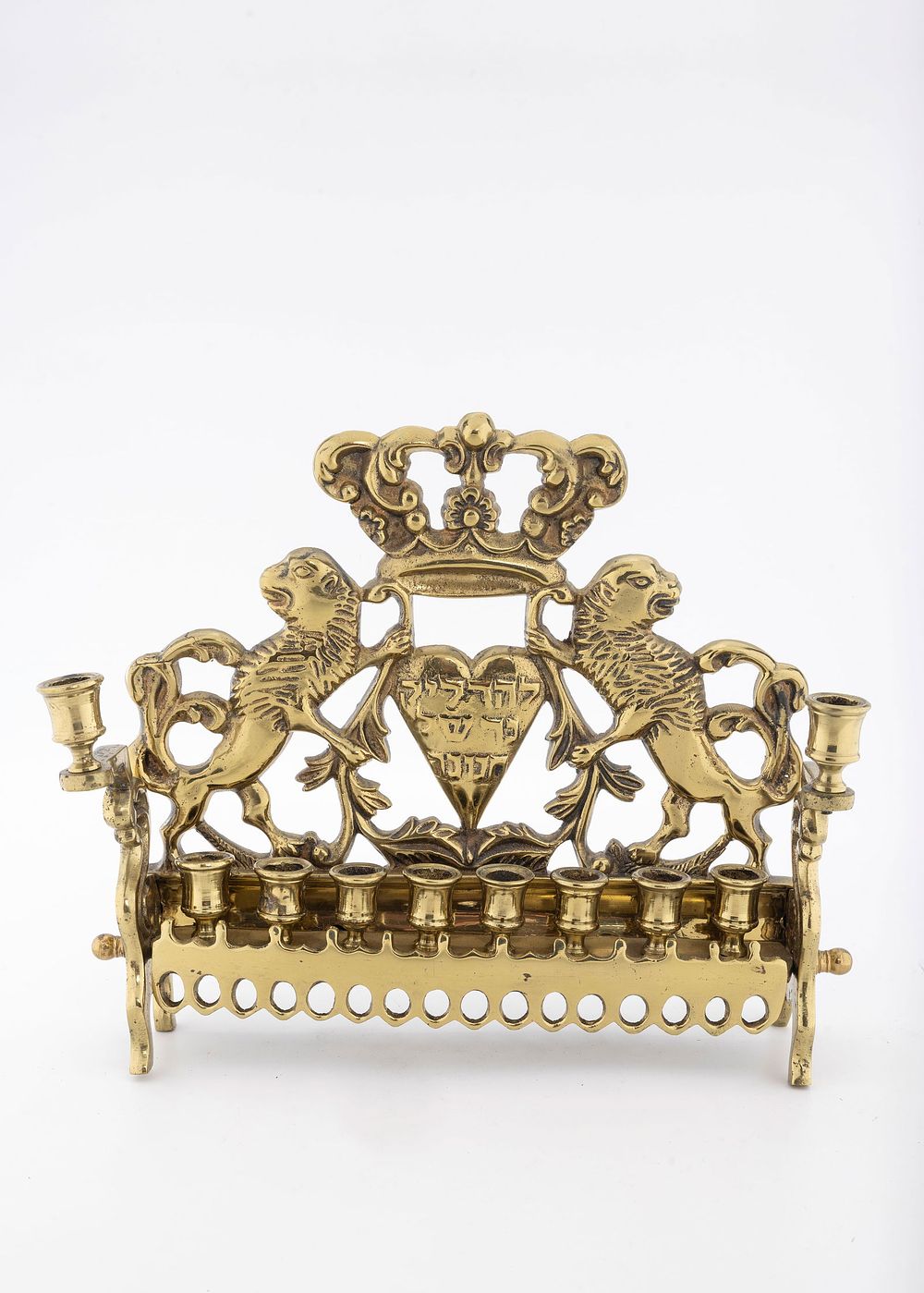 A BRASS HANUKKAH LAMP. Poland or USA, c. 1900. The backplate is decorated with two outwardly 