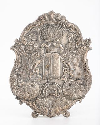 A SILVER TORAH SHIELD. Continental,. Hand chased with lions, flowers, scrolls and a decalogue. 