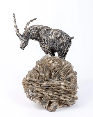 A SOLID SILVER SCULPTURE OF A MOUNTAIN GOAT OR RAM ON A MICA BASE. A SOLID SILVER MOUNTAIN GOAT 