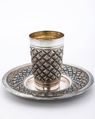 A STERLING SILVER KIDDUSH CUP AND PLATE BY HADDAD BROTHERS. Israel, c. 2000. In a basket weave 