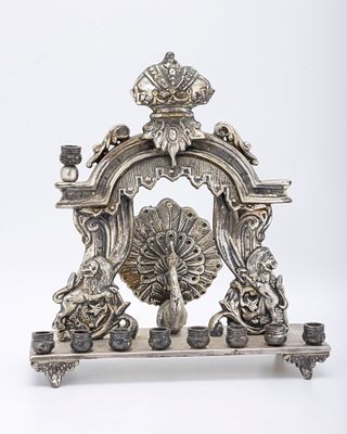 A SILVERPLATED PEACOCK FORM HANUKKAH LAMP. Austria, c. 1900. On a rectangle base with candle 