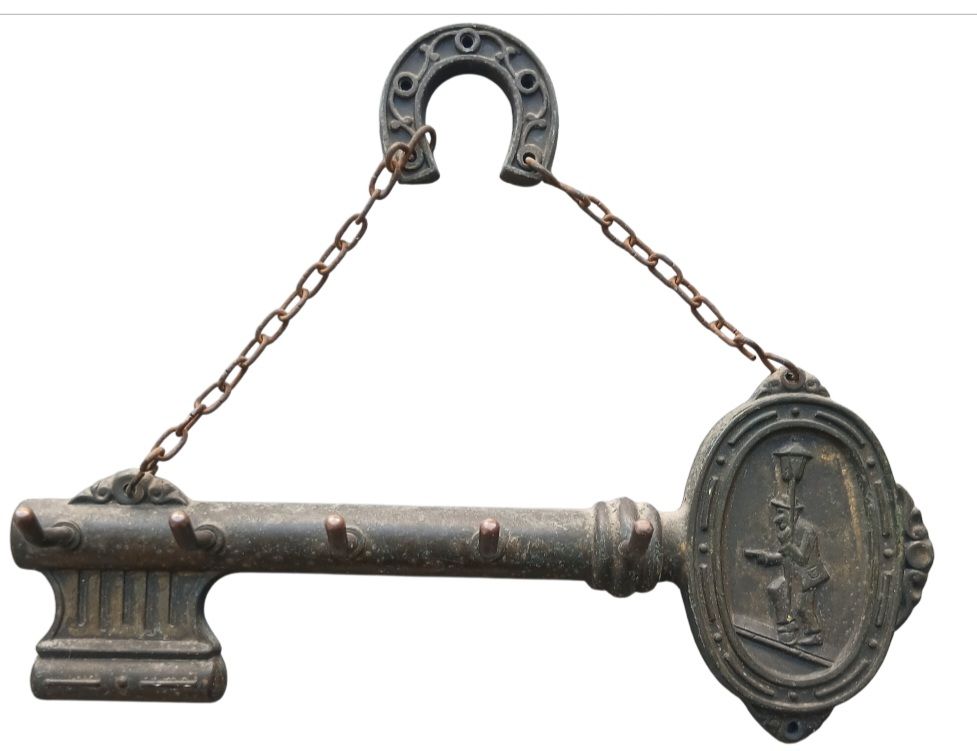 מתלה קיר למפתחות עשוי נחושת מעוצב בדוגמת מפתח עם תבליט גבר עומד מתחת לפנס רחוב חלק עליון בדוגמת 