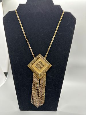 Gold Toned Filigree Pendant Necklace with Chain Tassel. A gold-toned necklace featuring a large 
