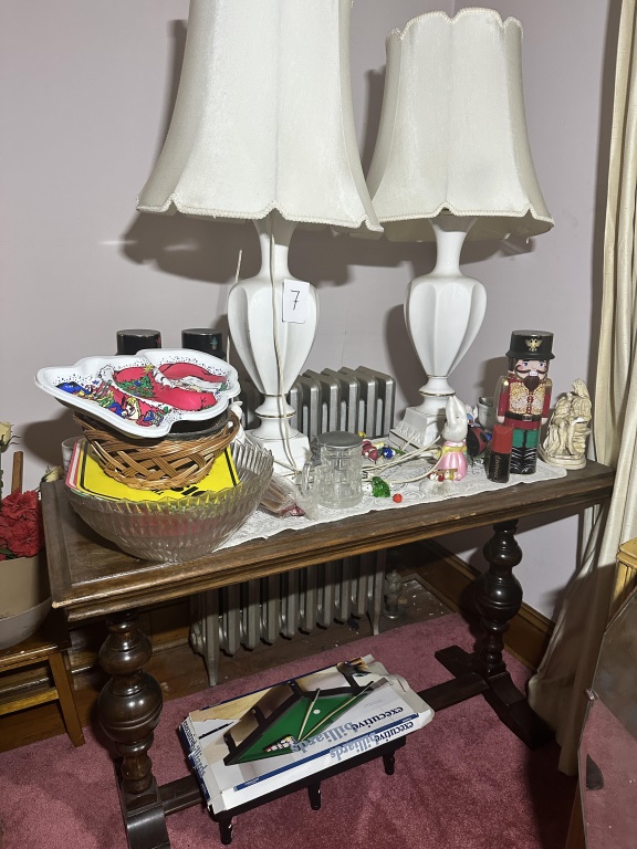 Table With Lamps & Contents wood table with turned legs, pair of white table lamps, glass bowl, basket, holiday plate, nutcracker, small fig