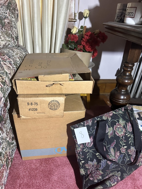 Box Lot Of Glass Plates & Silverplate estate box lot with glass cake plates, trays, candlestick, and assorted serving pieces.