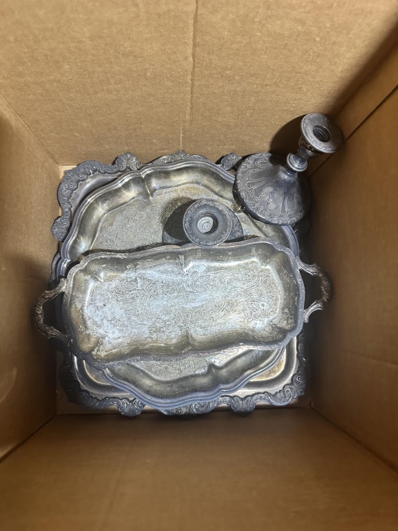 Box Lot Of Glass Plates & Silverplate estate box lot with glass cake plates, trays, candlestick, and assorted serving pieces.