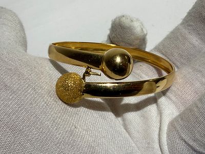 פריט 184. צמיד קשיח זהב צהוב 21 קראט בעיצוב מודרני ייחודי, עם אלמנטים כדוריים בגימור מט ומבריק. 