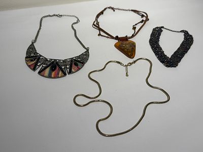 לוט ארבעה שרשראות בעיצובים שונים. החומרים לא נבדקו.