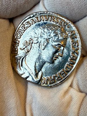 מטבע דקורטיבי בסגנון רומי עתיק, עם דיוקן הקיסר מרקוס אורליוס אלכסנדר בצדו האחד, ובצדו השני דמות 