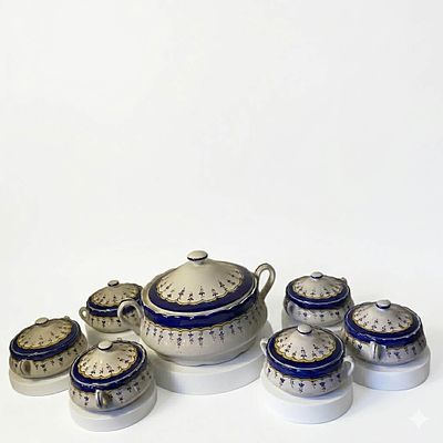 סט הגשה קרמי בסגנון קלאסי-מלכותי, הכולל 7 חלקים: קערת הגשה מרכזית גדולה עם מכסה וידיות צד, לצד 