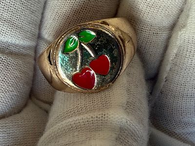 Signet ring made of gold-tone base metal, featuring a round plate decorated with a cherry motif 