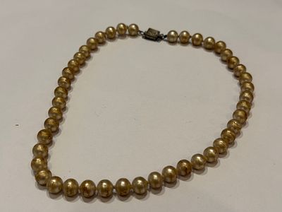 שרשרת עשויה חרוזים עגולים בגימור פנינים סינתטיות בגוון זהוב חמים.