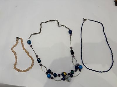 לוט הכולל שלוש שרשראות בגווני כחול, סגול וורוד עדין, בעיצוב אלגנטי ונעים לעין.