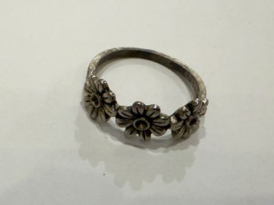 Decorative ring with a delicate design featuring three flowers connected along the top of the 