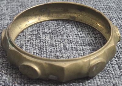 Vintage cast brass bangle bracelet with a closed band, a faceted outer surface and raised round 