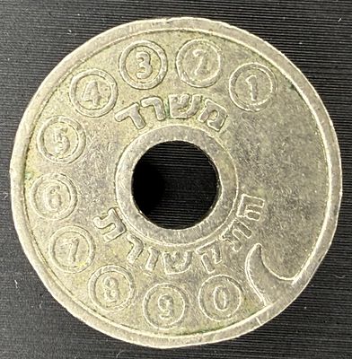 An Israeli public telephone token (asimon) with a central hole and two grooves. One side shows 