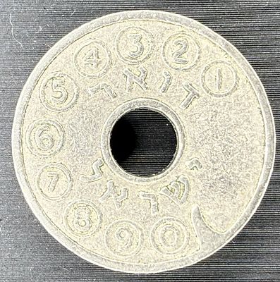 A classic Israeli public telephone token (asimon) with a central hole and two grooves. One side 