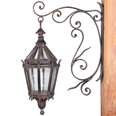 CAST IRON AND GLASS LANTERN HANGING FROM AN IRON BRACKET C 1920. Cast iron and glass lantern 