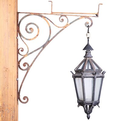 CAST IRON LAND GLASS LANTERN HANGING FROM AN IRON BRACKET C 1920. BRACKET IS INVERTED IN PHOTO AND. 