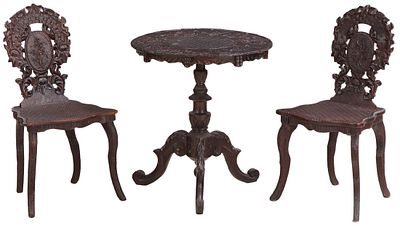 A PAIR OF CARVED MAHOGANY BLACK FOREST SIDE CHAIRS WITH MATCHING OCCASIONAL TABLE C 1890. A 