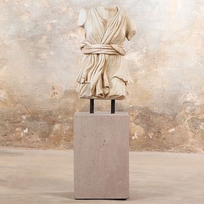 A CARVED MARBLE ROMAN STYLE TORSO MOUNTED TO A STONE BASE. A carved marble Roman style torso 