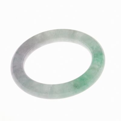 Jade Bangle China, 20th century. Green jade with attractive, dark and white cloud-like 