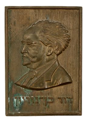 דוד בן גוריון – לוחית עם דיוקנו ובובה בדמותו. 1. לוחית פליז יצוקה עם דיוקן בן גוריון, מעשה ידי 