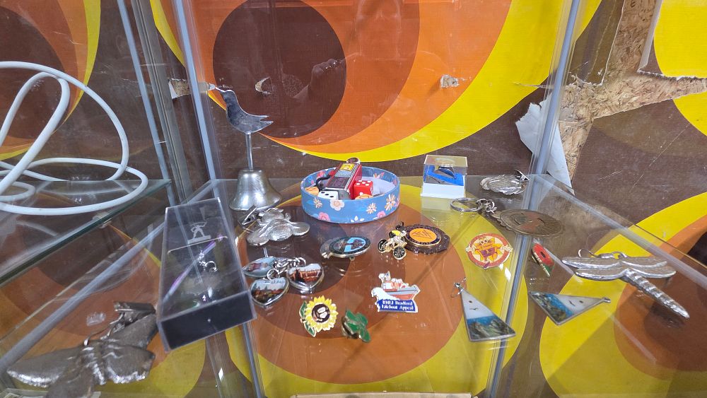 Lot 620 – A Collection of Enamel Pins, Keychains, and Silver-Toned Trinkets