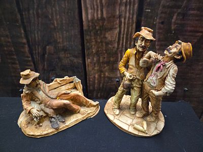 A Pair of Rustic Figurines Depicting Men. A pair of decorative figurines depicting men in rustic 