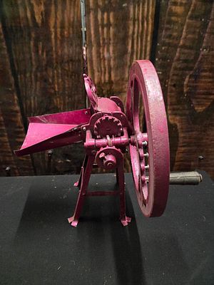 Vintage Magenta Cast Metal Hand Cranked Corn Sheller. A magenta-coloured vintage hand-cranked 