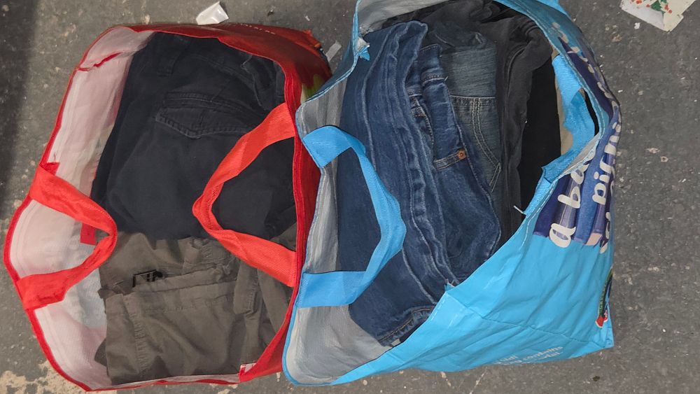 Lot 427 – Two Bags of Clothing. Including Denim Jeans and Trousers