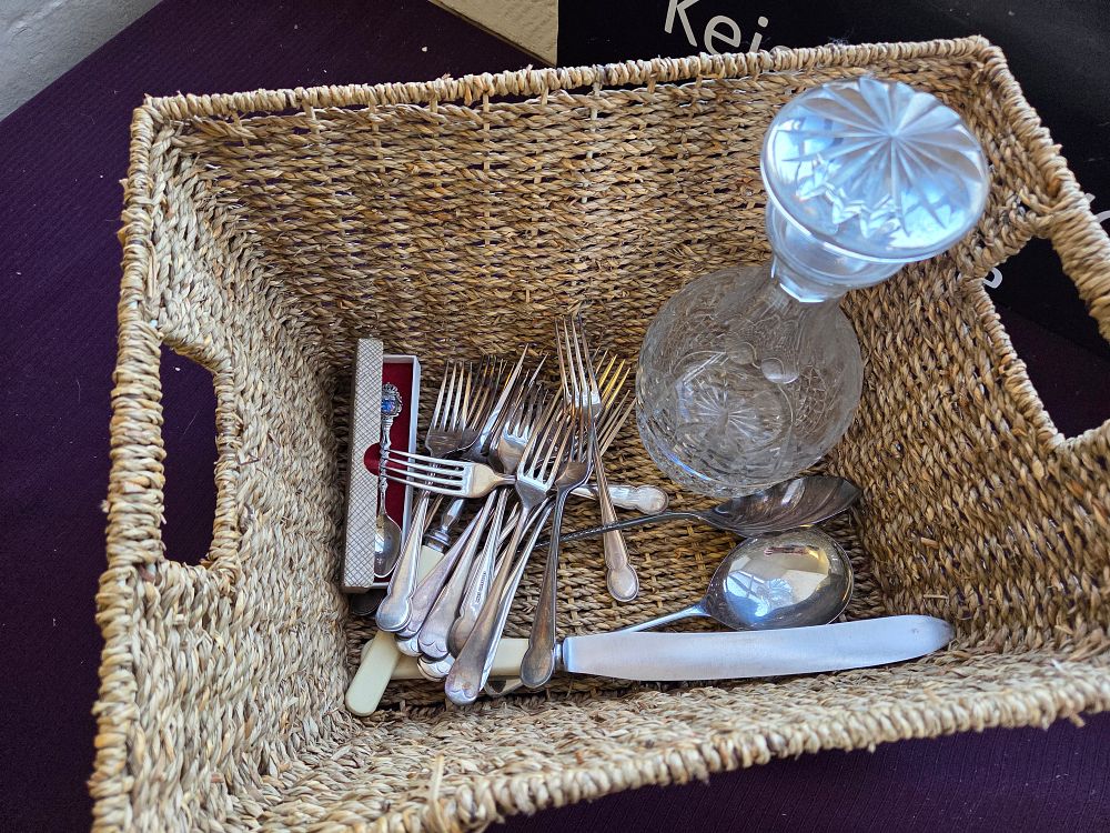Lot 382 – A Collection of Silver Plated Flatware, a Cut Glass Decanter, and a Souvenir Spoon in a Woven Basket