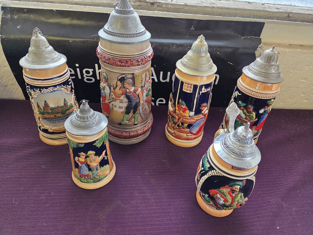 Lot 612 – A Group of Six German Souvenir and Folk Scene Relief Lidded Beer Steins