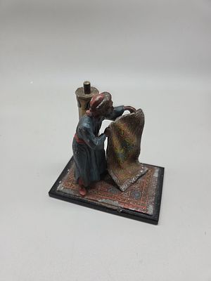 An Orientalist Cold-Painted Metal Figure of a Carpet Merchant with Table Lighter in the Style 