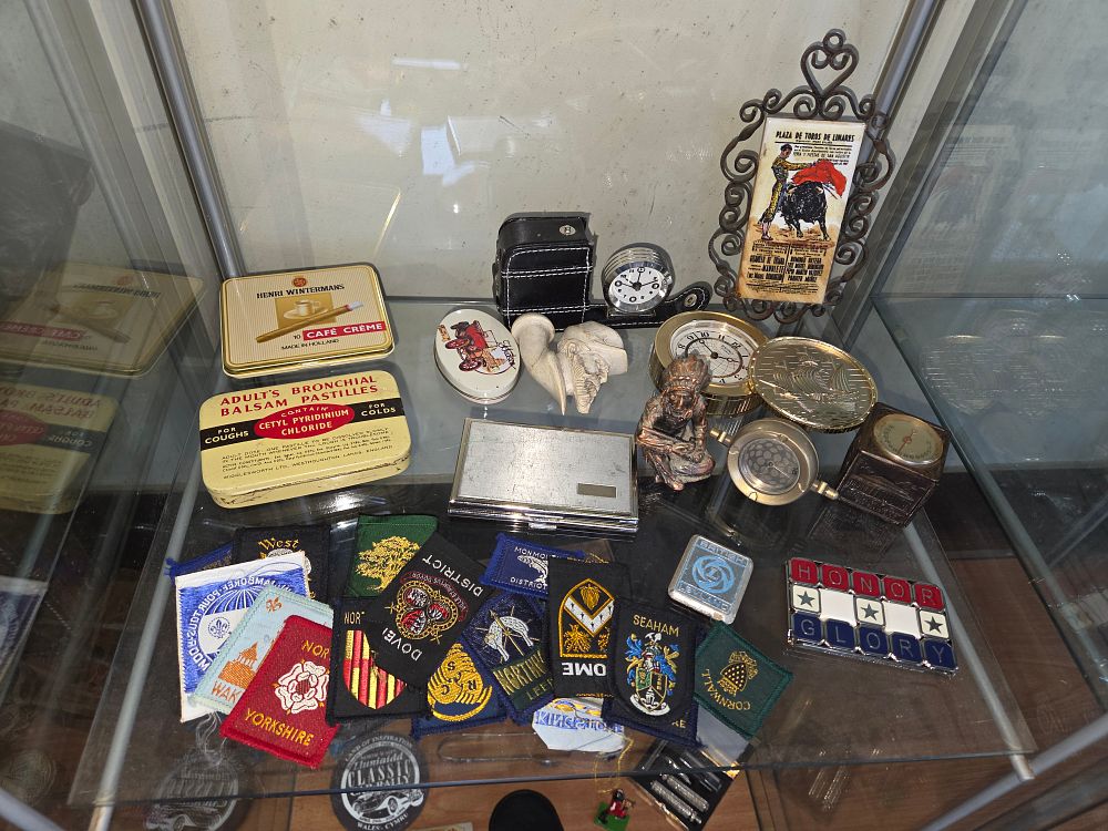 Lot 619 – An Assortment of Vintage Advertising Tins, Horological Instruments, and Embroidered Patches