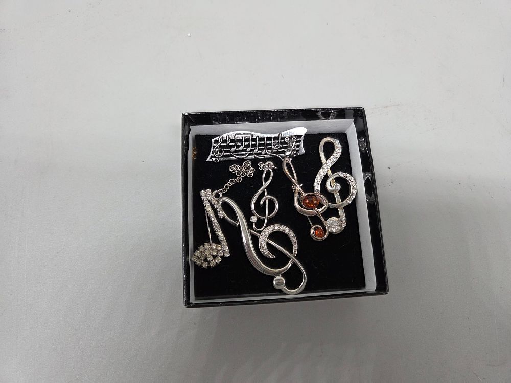 Lot 246 – A Collection of White Metal and Rhinestone Musical Notation Brooches and Pins