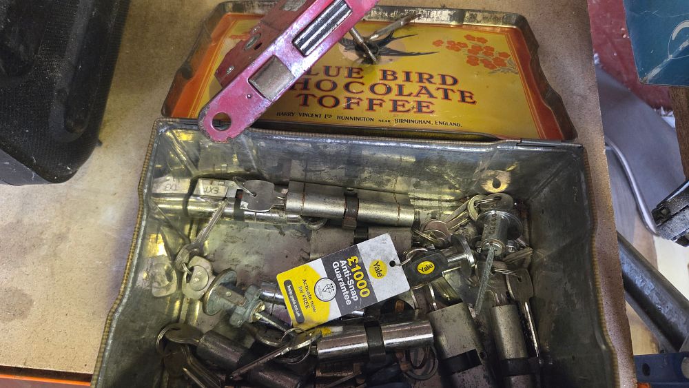 Lot 200 – An Assortment of British Door Locks and Keys in a Vintage Blue Bird Toffee Tin
