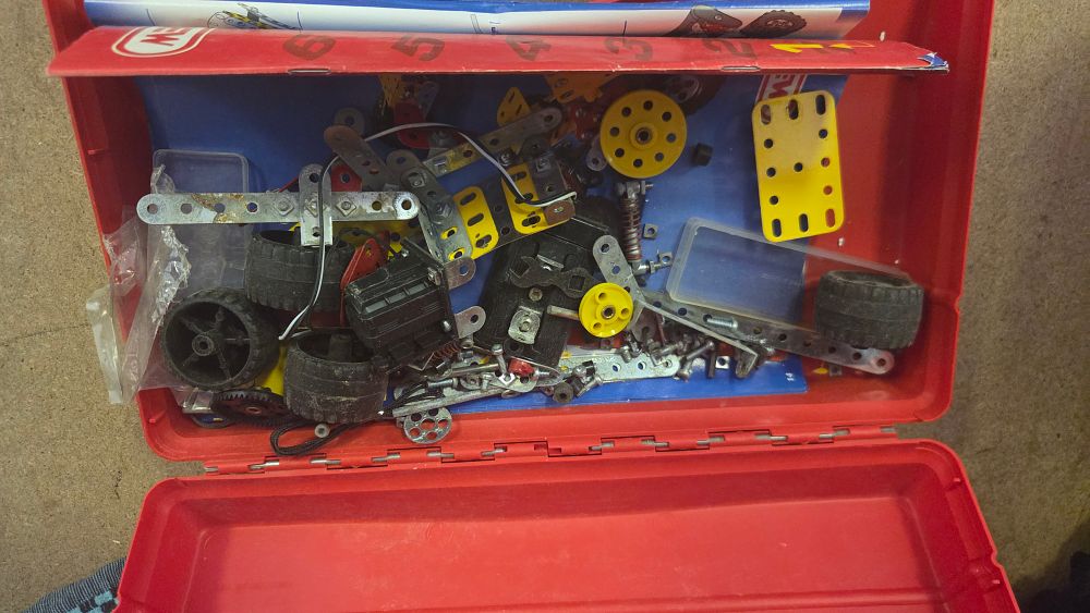 Lot 153 – An Assortment of Meccano Construction Toy Components in a Red Plastic Carrying Case