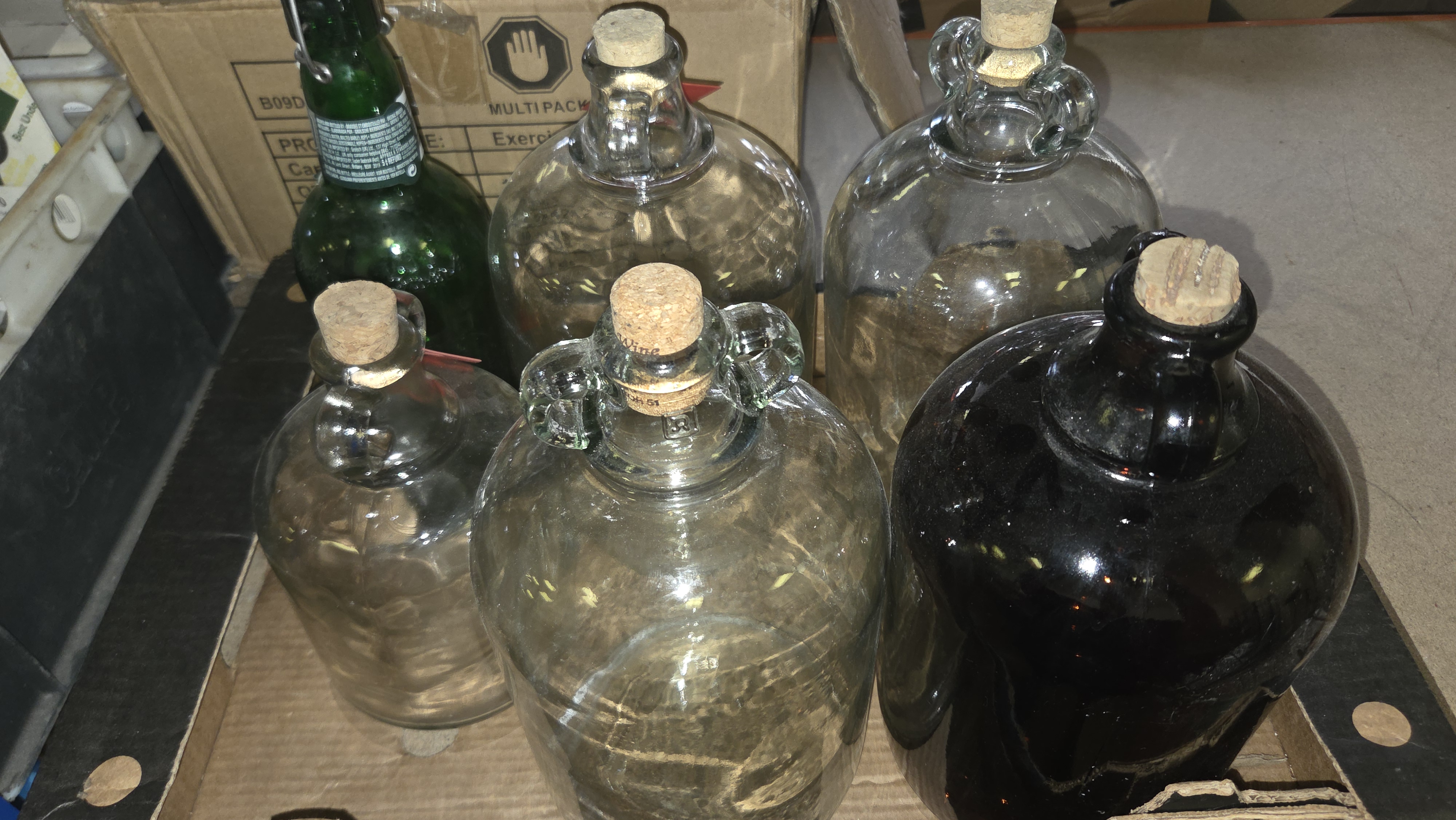 A Collection of Glass Demijohns and a Swing-Top Bottle