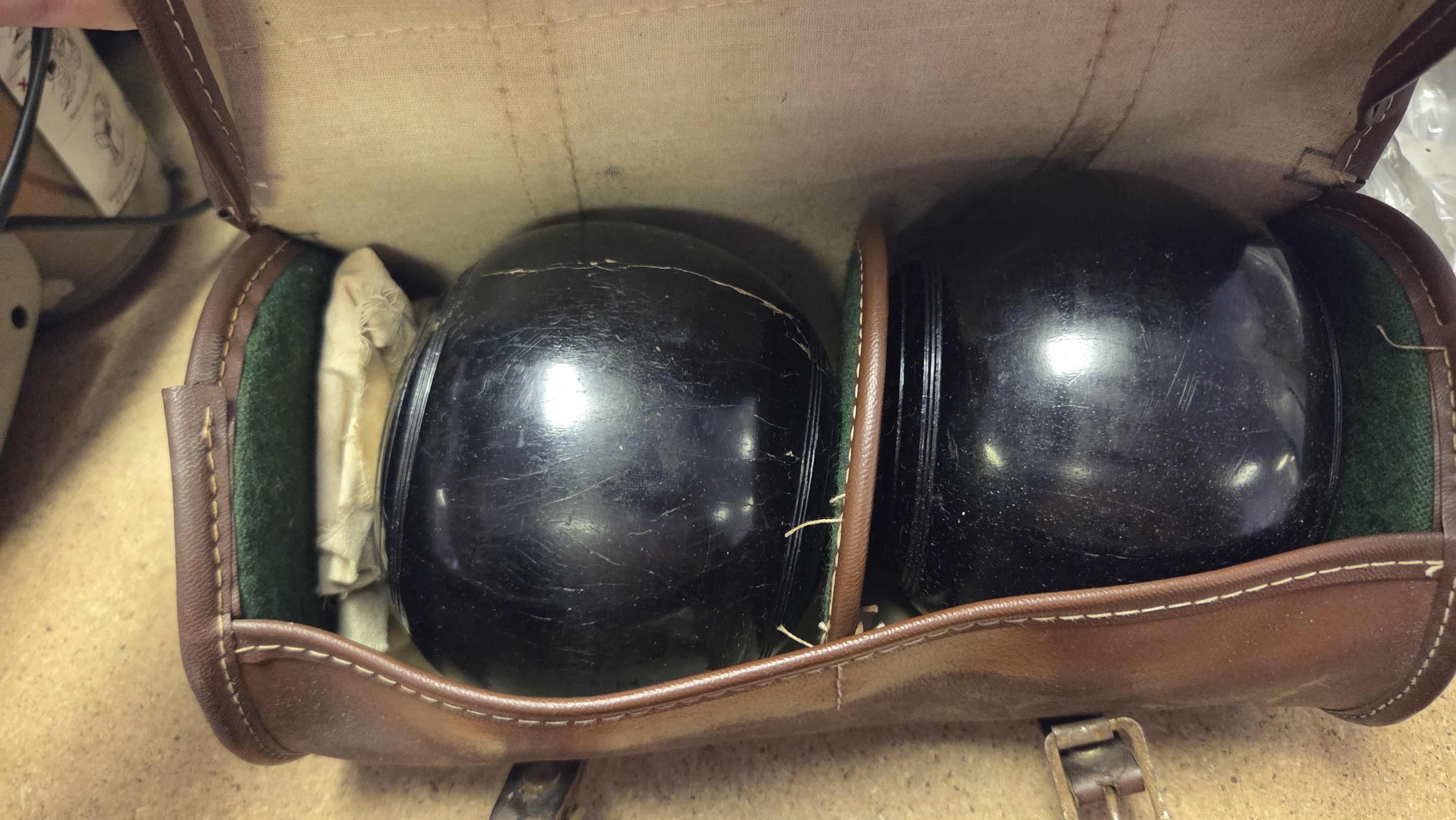 A Pair of Vintage Black Composition Lawn Bowls in a Patented Leather Carrying Case