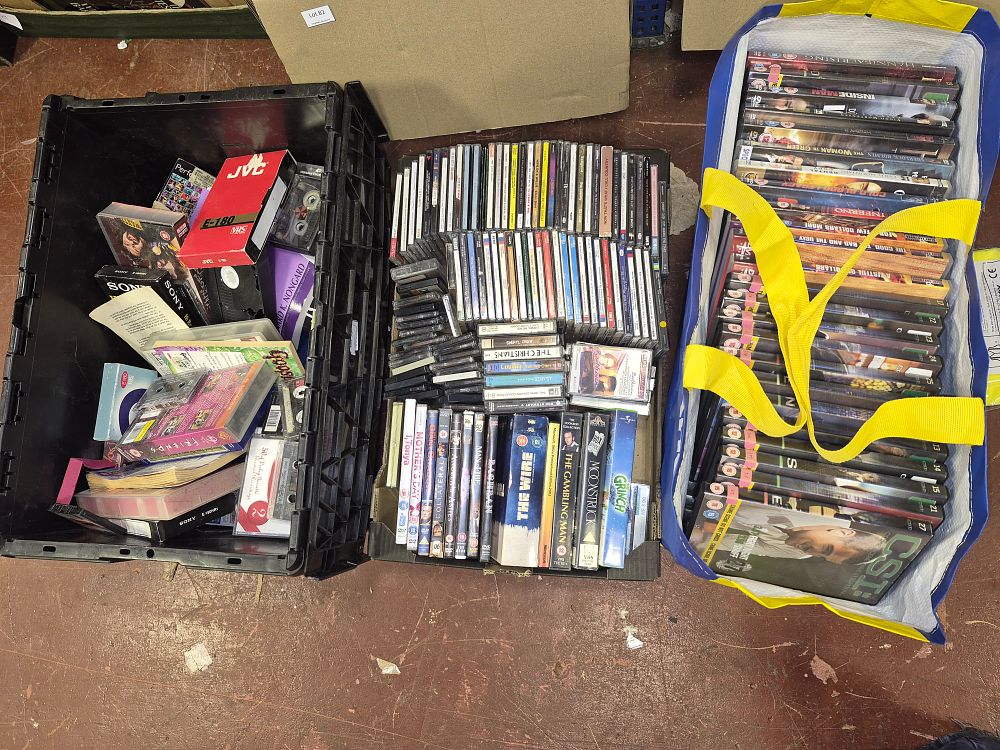 Lot 185 – Two Boxes and Bag of DVDs, CDs, VHS Tapes, and Audio Cassettes Including CSI, The Wire, and The Good, The Bad and The Ugly