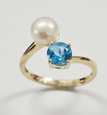 A 14k Yellow Gold Pearl and Blue Topaz Bypass Ring. This bypass-style ring is crafted in 14k 