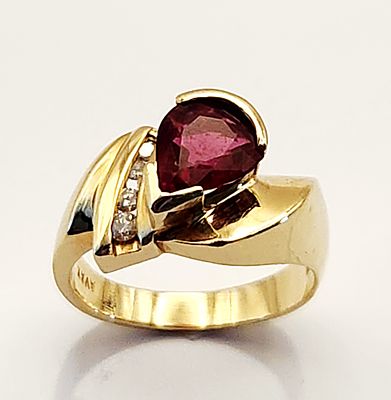 14K Garnet Ring 6 Grams. This 14 karat yellow gold ring features an asymmetrical bypass design. 