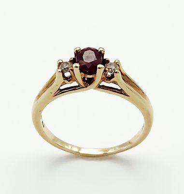 10K Gold Ruby Ring 3 Grams. A 10kt yellow gold three-stone ring featuring a central round-cut 