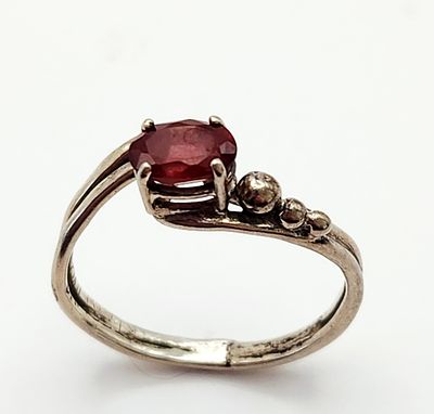 Sterling Ruby Ring 2.3 Grams. A sterling silver bypass ring featuring an oval ruby and three 