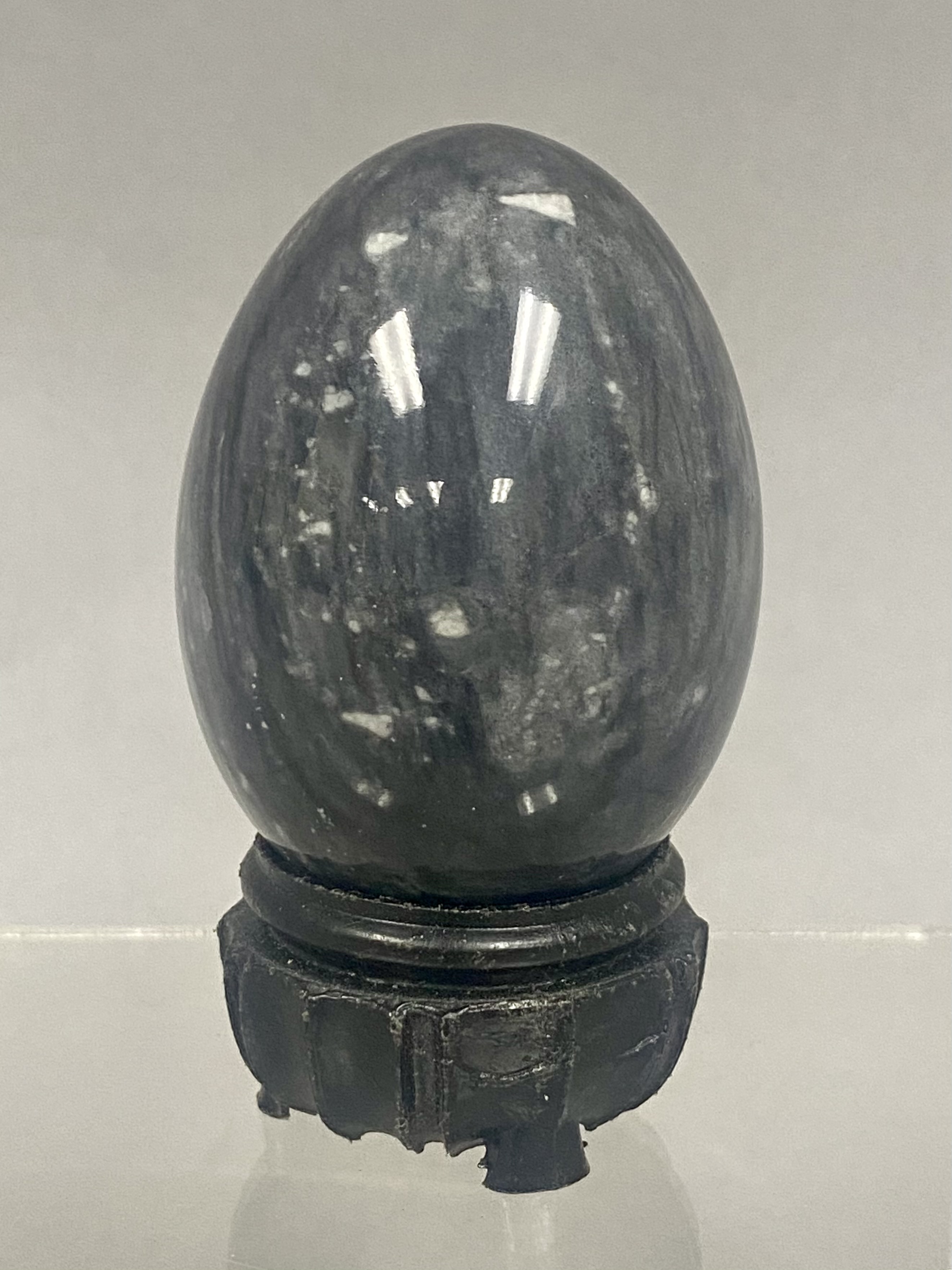 Polished Mottled Gray Stone Egg on a Carved Wooden Stand