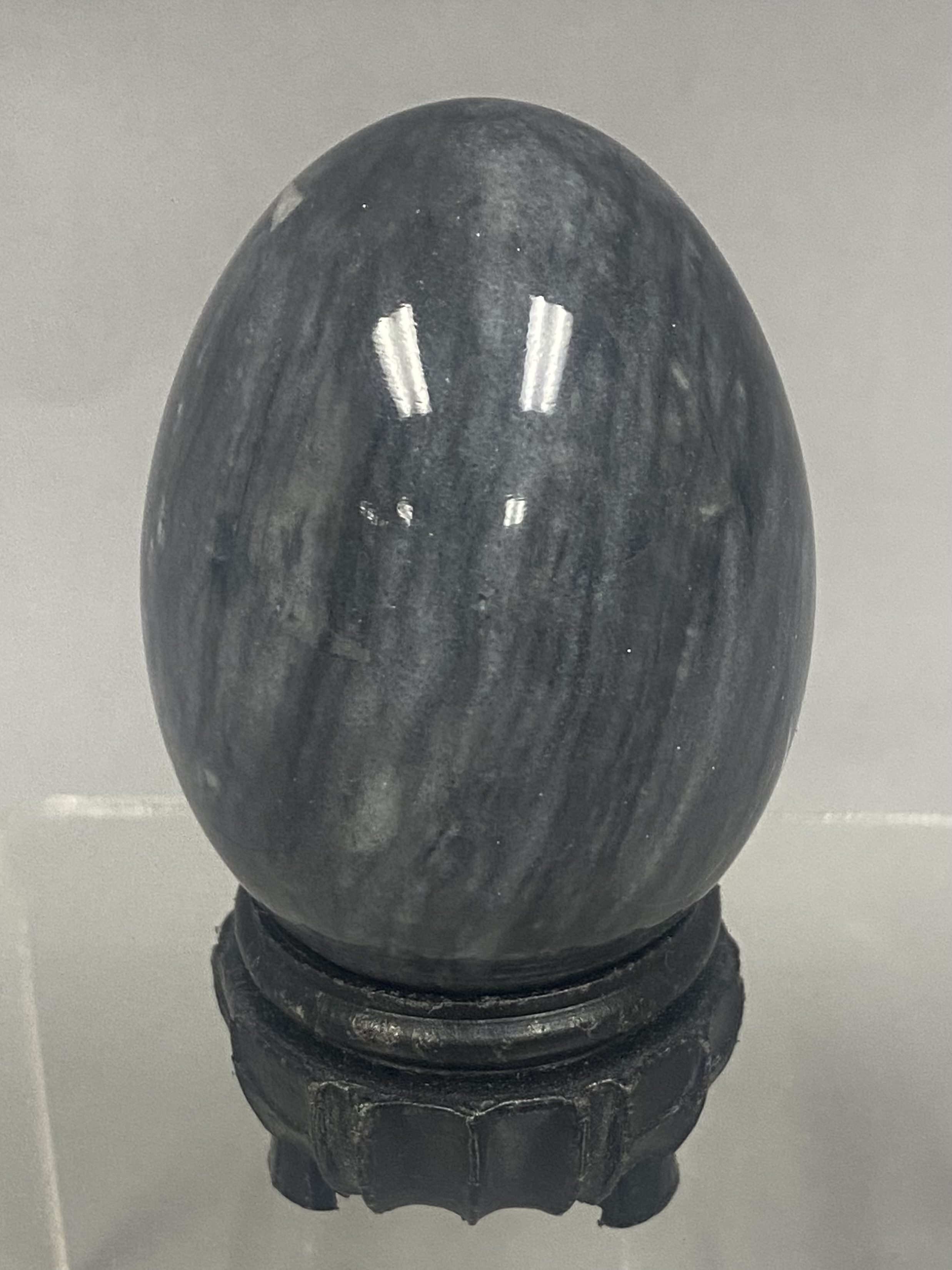 Polished Mottled Gray Stone Egg on a Carved Wooden Stand