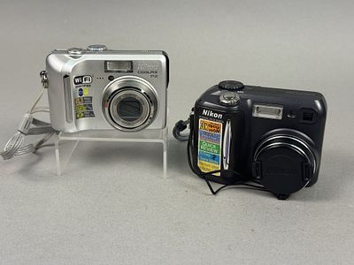 Two Nikon Coolpix Digital Cameras. This lot features a silver Nikon Coolpix P2 and a black Nikon 