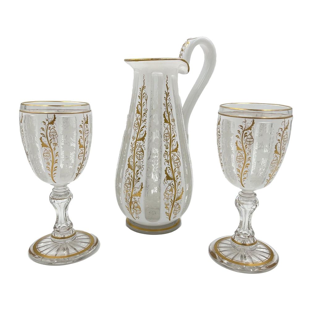 BOHEMIAN GLASS EWER AND CUPS WITH GILT HIGHLIGHTS A Bohemian glass ewer accompanied by two cups, 