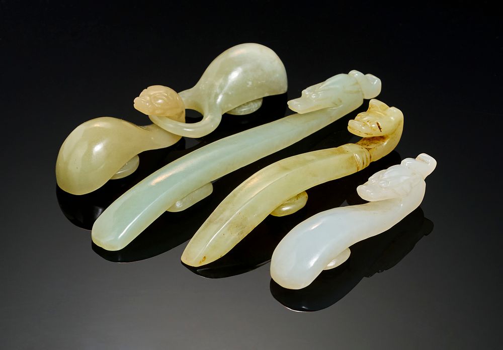 Lot 253: A GROUP OF FOUR CHINESE CARVED JADE BELT HOOKS